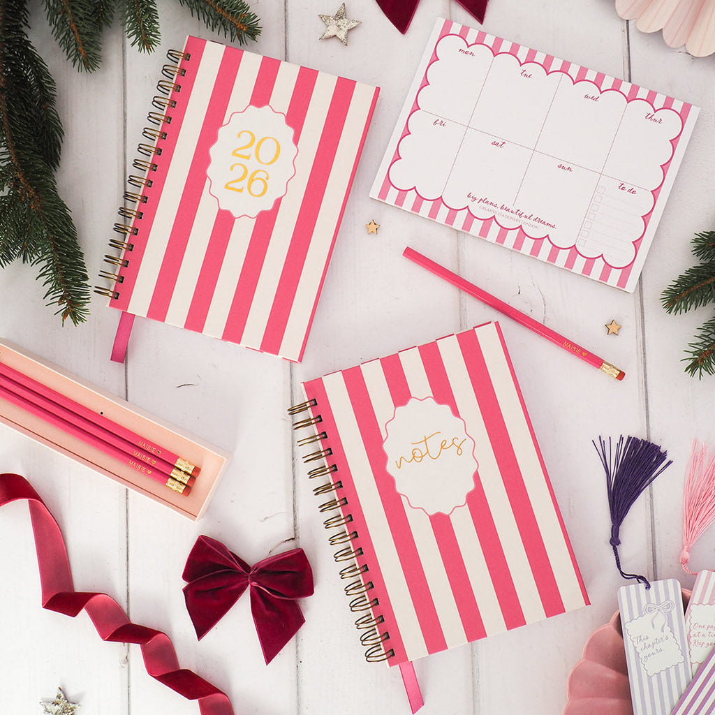 Pink and white striped notebooks with decorative elements on a wooden surface