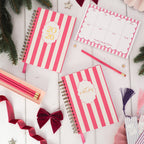 Pink and white striped notebooks with decorative elements on a wooden surface