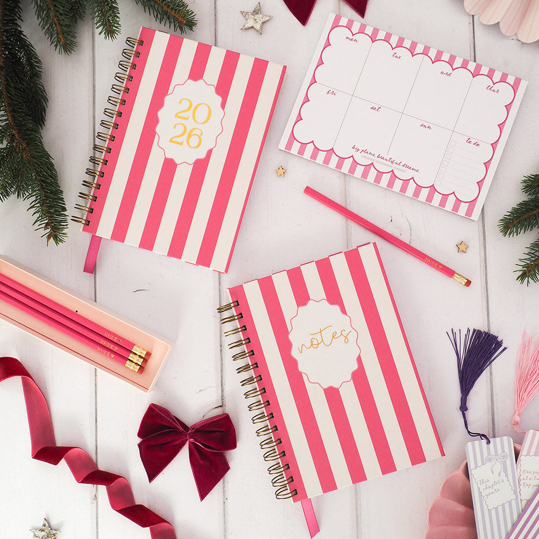 Pink and white striped notebooks with decorative elements on a wooden surface