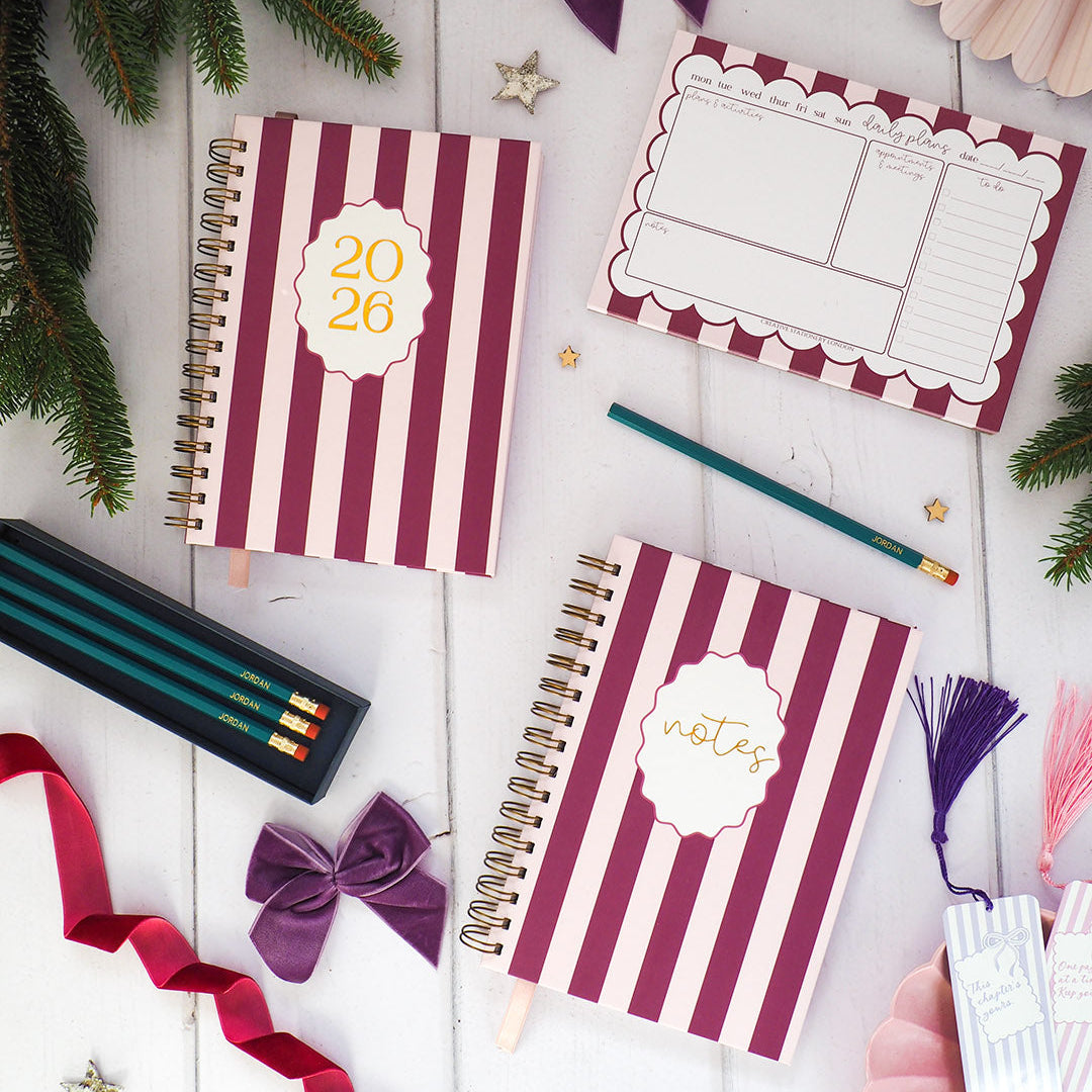 Two spiral-bound notebooks with striped design on a white surface with decorative items.