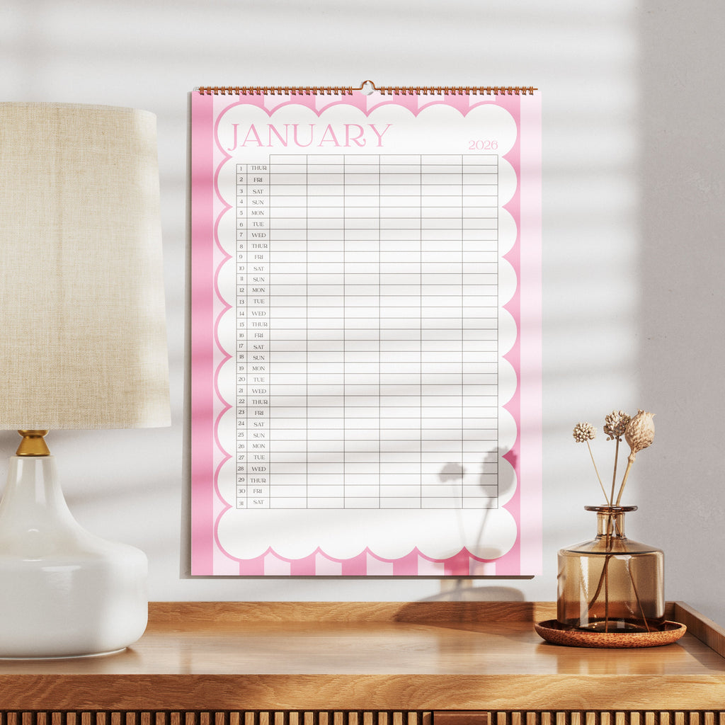 A3 Family Wall calendar for January on a wooden surface with a lamp and decorative items.