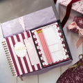 Notebook in grey gift box with stationery items on a decorative surface