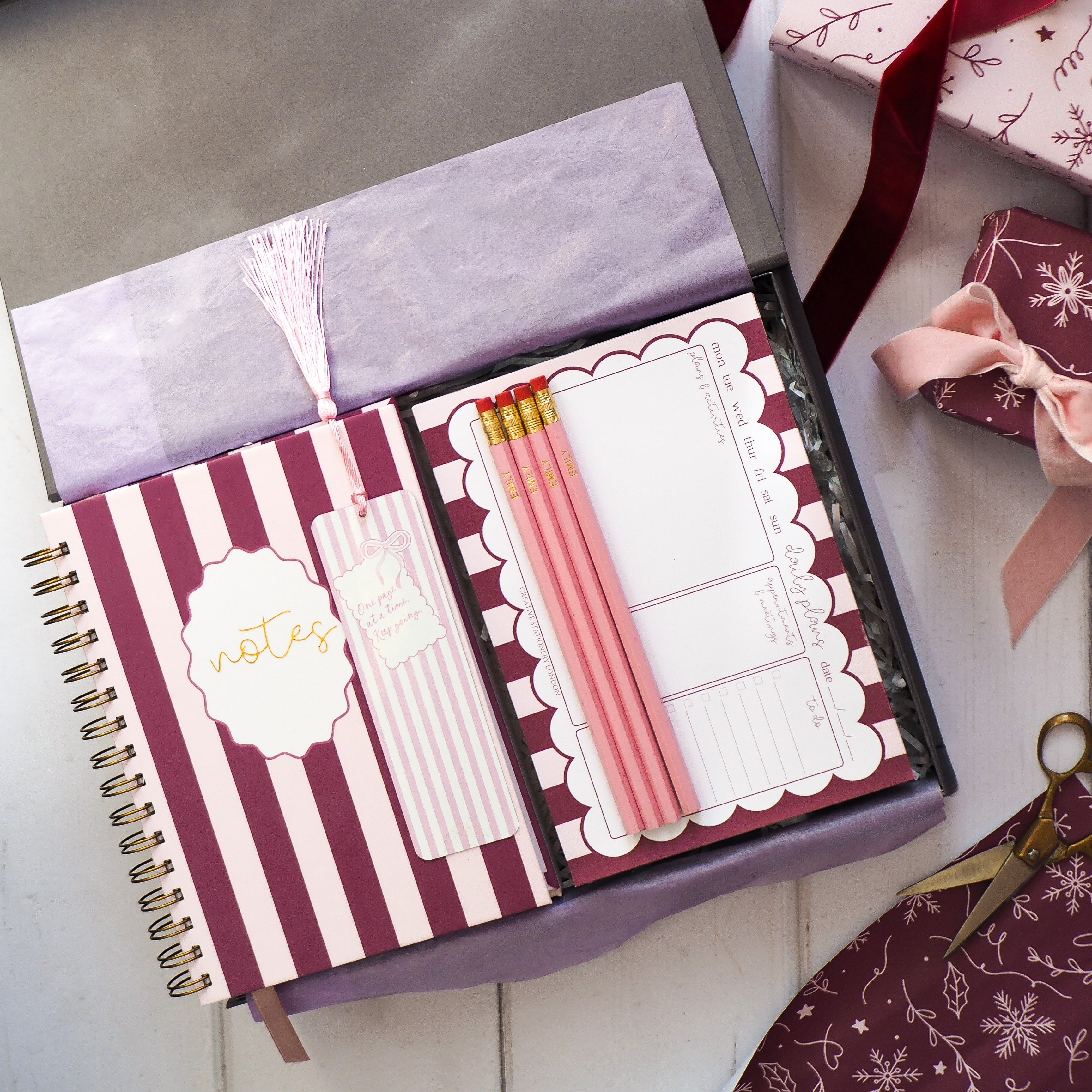 Notebook in grey gift box with stationery items on a decorative surface