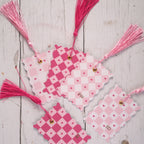 Pink and white chequered bookmark with tassels on a wooden surface