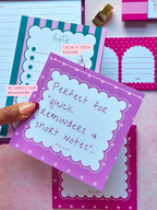 A hand holds a purple square memopad with a white scalloped border and the text 'Perfect for quick reminders and short notes.' Pink and teal stationery sheets are arranged around it on a pink surface, with small printed labels describing sheet size and quantity.