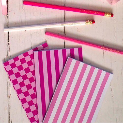 Pink stationery items including notebooks, stickers, and a cup of tea on a wooden surface.