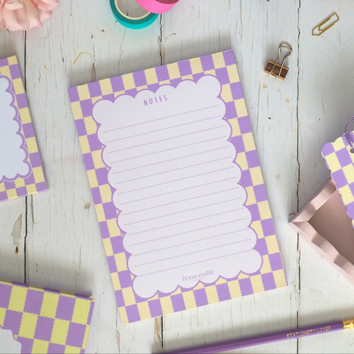 Checkered notepad and stationery items on a wooden surface