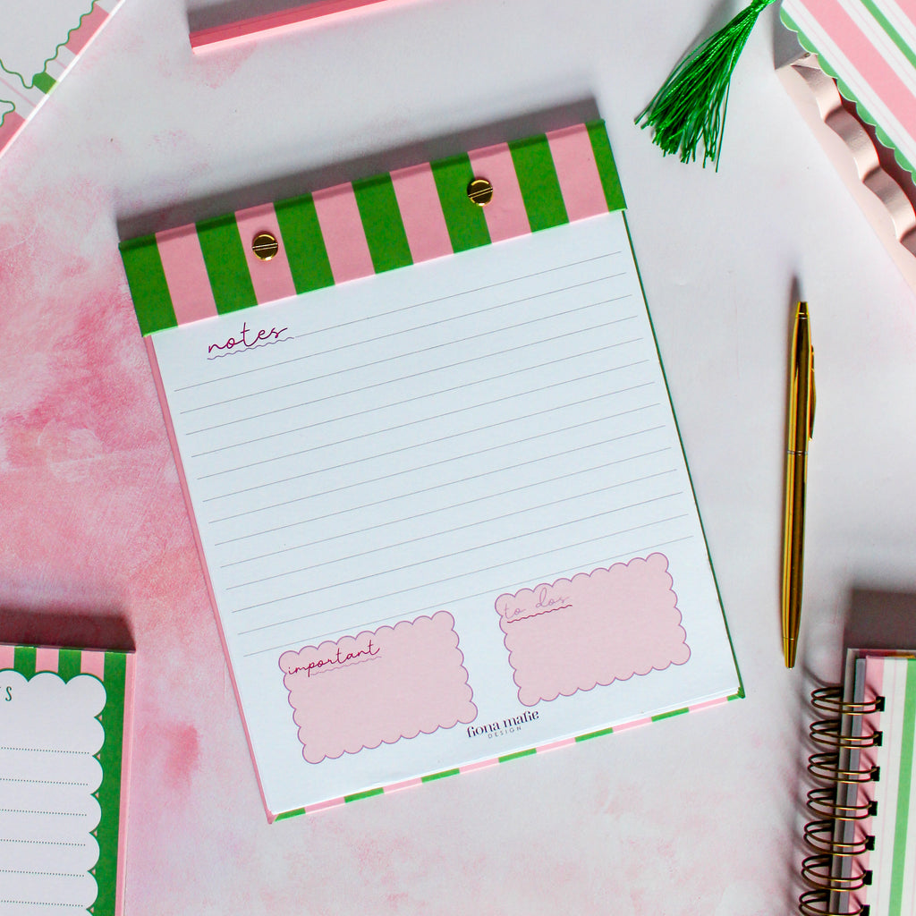 refillable notepad with green and pink striped cover on a white surface