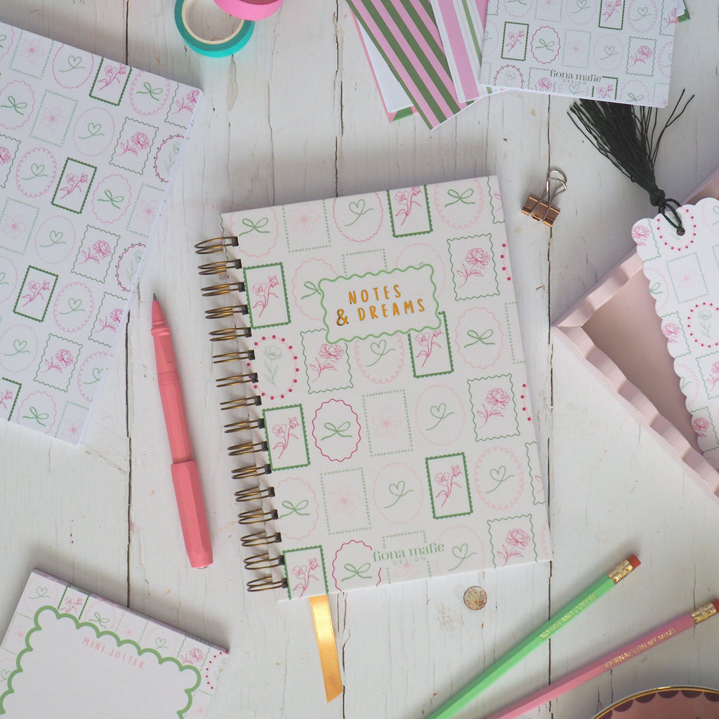Stationery items including notebooks, pens, and a teacup on a wooden surface.