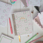 Stationery items including notebooks, pens, and a teacup on a wooden surface.