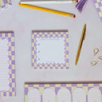 Checkered notepads with purple and yellow design on a light gray background
