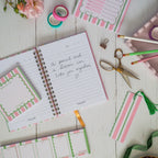 Notebook with printed pages and stationery items on a wooden surface