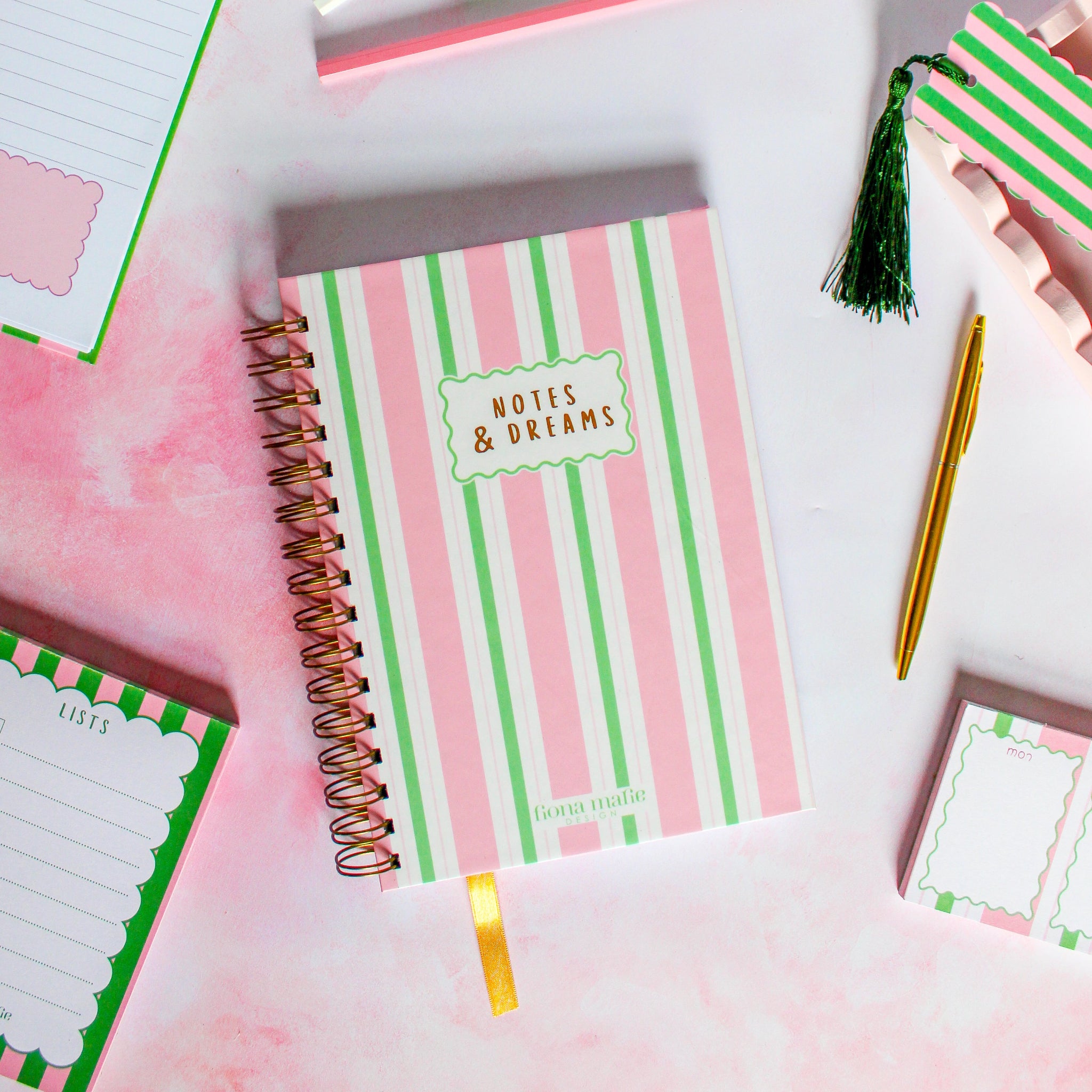 Notebook with pink and green striped cover labeled 'Notes & Dreams' on a light background.